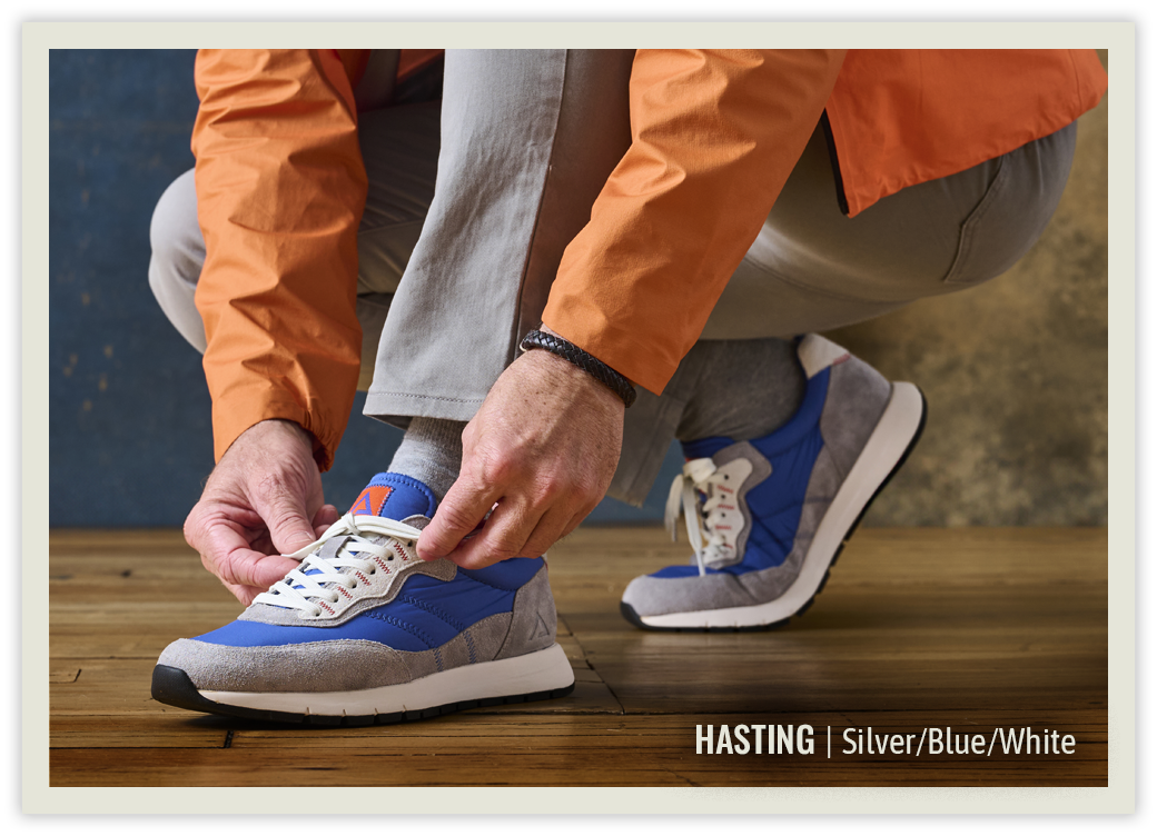 A man wearing the Hasting sneaker in silver/blue/white.